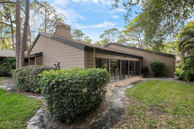 view of side of property with a lawn and a sunroom