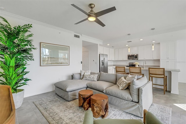 living room featuring ceiling fan, sink, and crown molding