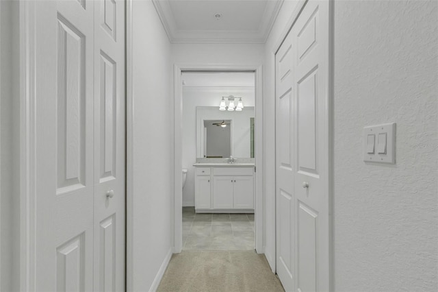 corridor with crown molding, light colored carpet, and sink