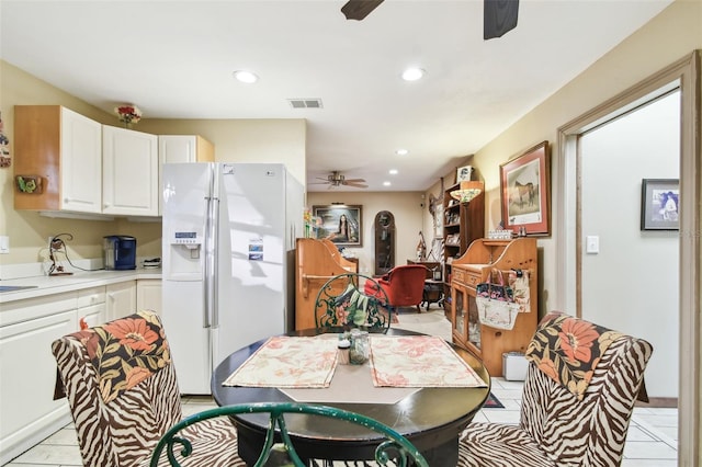 kitchen featuring white refrigerator with ice dispenser, light tile patterned floors, white cabinets, and ceiling fan