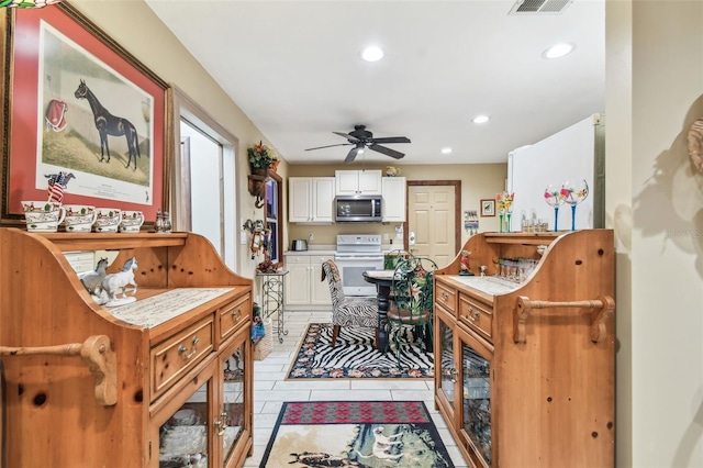 interior space with ceiling fan, white cabinetry, white stove, and light tile patterned floors