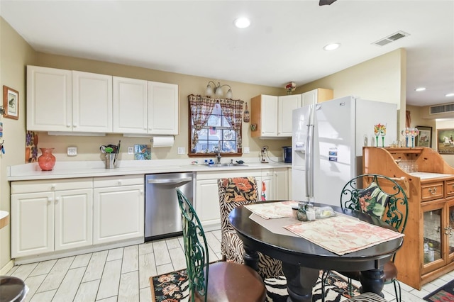 kitchen featuring dishwasher, white cabinetry, white fridge with ice dispenser, and sink