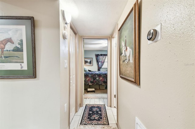 hallway with light tile patterned floors and a textured ceiling