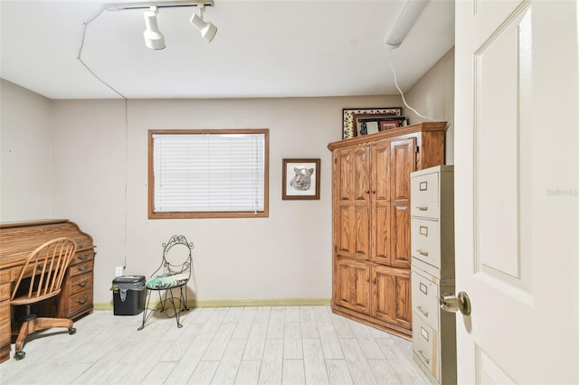 office with light hardwood / wood-style floors and track lighting