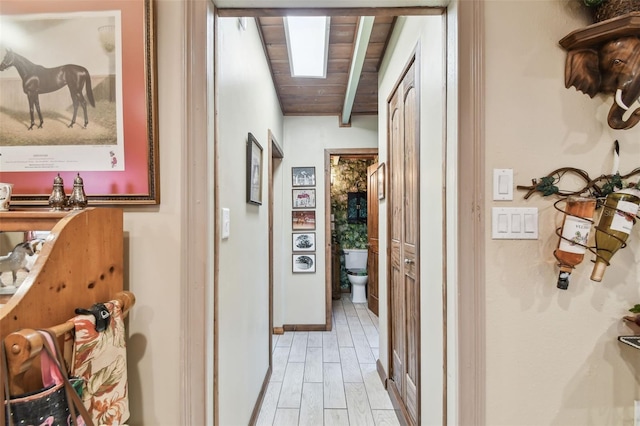 hall featuring beam ceiling, wooden ceiling, and light wood-type flooring