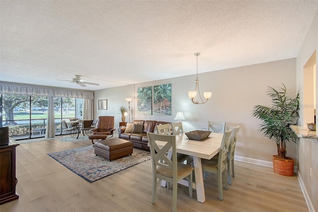 dining room featuring ceiling fan with notable chandelier, light hardwood / wood-style floors, and a textured ceiling