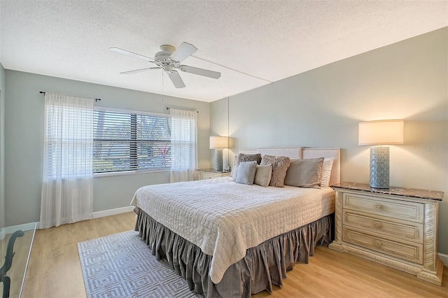 bedroom with ceiling fan, light hardwood / wood-style floors, and a textured ceiling