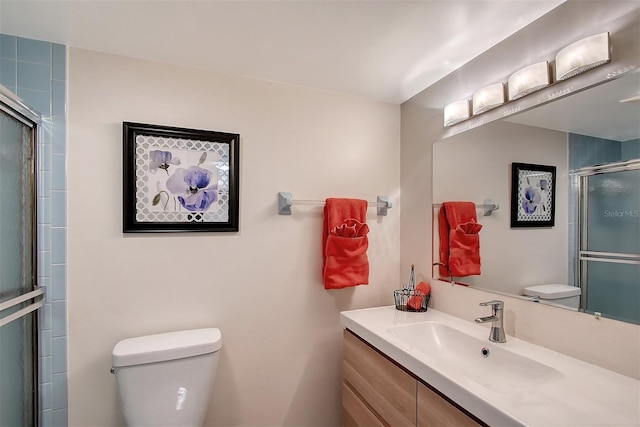 bathroom featuring vanity, an enclosed shower, and toilet