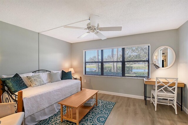 bedroom with ceiling fan, light hardwood / wood-style flooring, and a textured ceiling