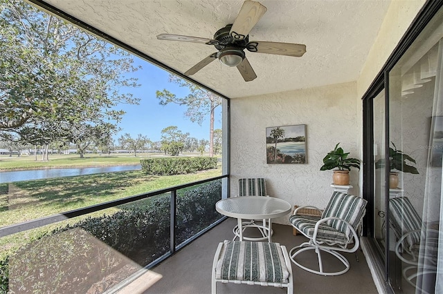 sunroom / solarium with a water view and ceiling fan