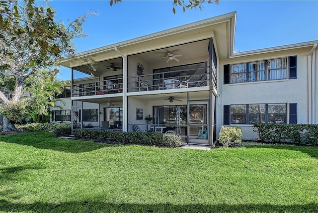 rear view of property with a balcony, a yard, and ceiling fan