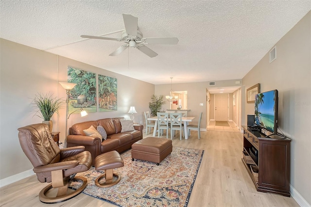 living room with ceiling fan, light hardwood / wood-style floors, and a textured ceiling