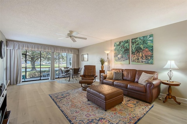 living room featuring ceiling fan, light hardwood / wood-style flooring, and a textured ceiling