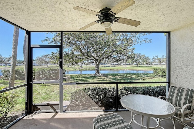 sunroom / solarium featuring a water view and ceiling fan