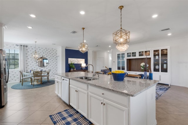 kitchen with decorative light fixtures, a center island with sink, sink, white cabinetry, and appliances with stainless steel finishes