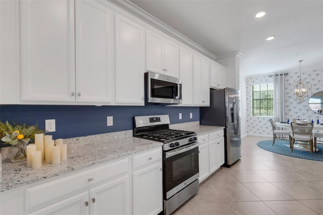 kitchen featuring a notable chandelier, pendant lighting, white cabinetry, appliances with stainless steel finishes, and light stone counters