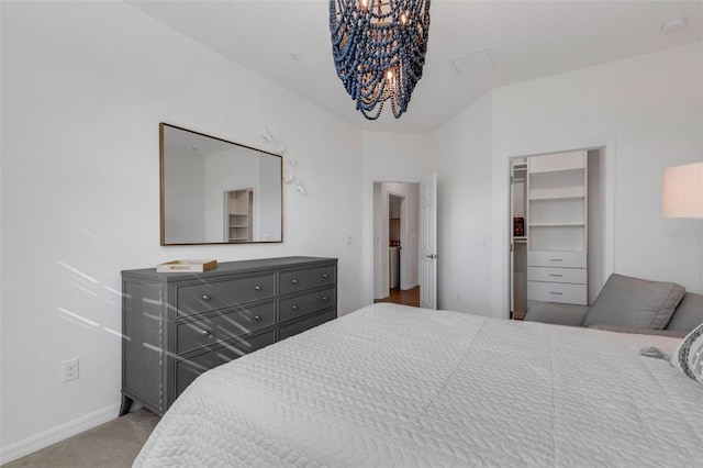 bedroom with light colored carpet, a closet, a spacious closet, and a chandelier