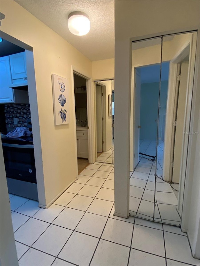 hall with light tile patterned floors, a textured ceiling, and sink