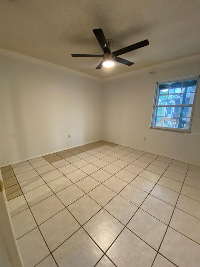 tiled spare room featuring ceiling fan and ornamental molding