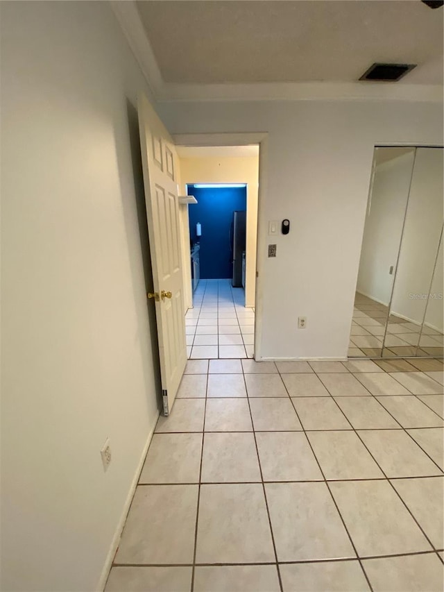 corridor featuring light tile patterned floors and ornamental molding