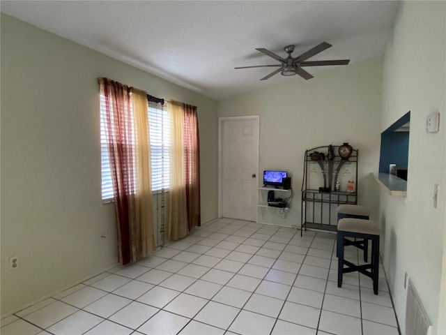 interior space with a textured ceiling, ceiling fan, and light tile patterned flooring