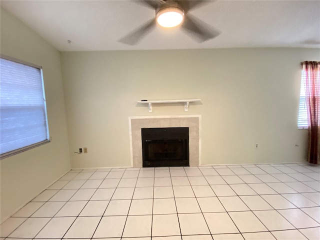 unfurnished living room with ceiling fan, a fireplace, and light tile patterned flooring