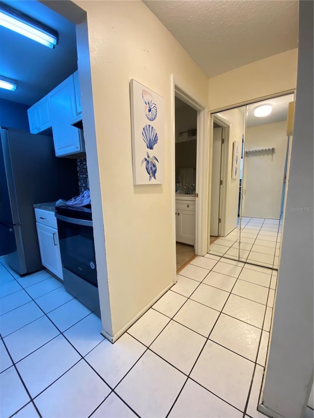 hall with sink, light tile patterned floors, and a textured ceiling