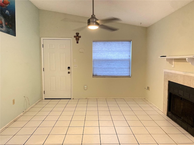 unfurnished living room featuring a tile fireplace, lofted ceiling, light tile patterned flooring, and ceiling fan