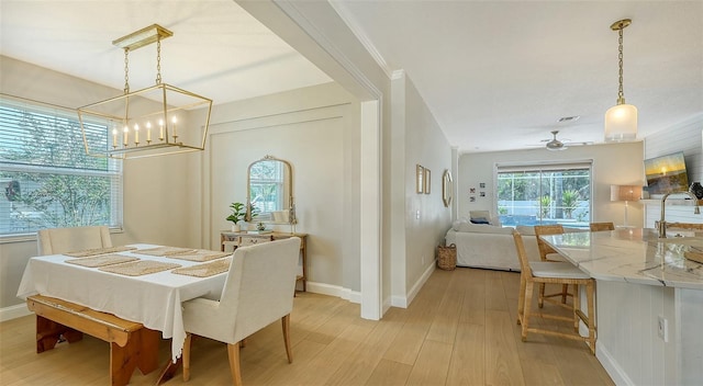 dining room with ceiling fan with notable chandelier, light wood-type flooring, and ornamental molding