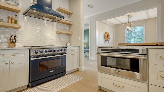 kitchen featuring stainless steel oven, wall chimney exhaust hood, hanging light fixtures, tasteful backsplash, and range with electric stovetop