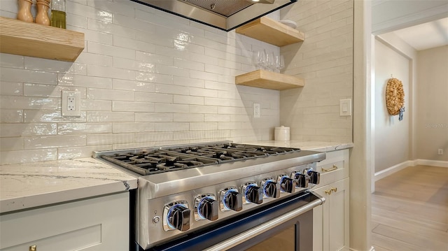 kitchen featuring decorative backsplash, high end stove, white cabinets, and light stone counters