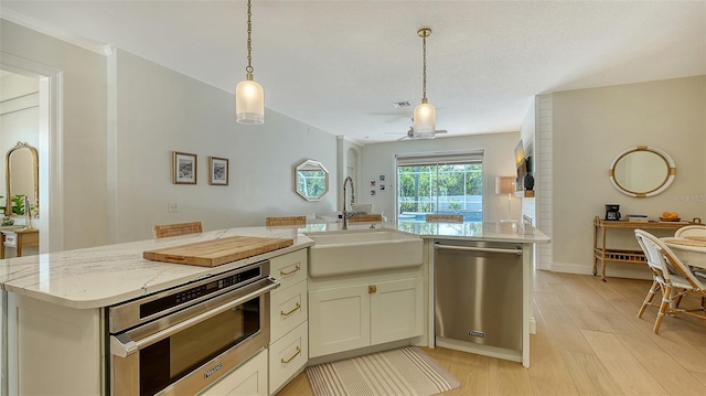 kitchen with a kitchen island with sink, sink, ceiling fan, light stone countertops, and stainless steel appliances