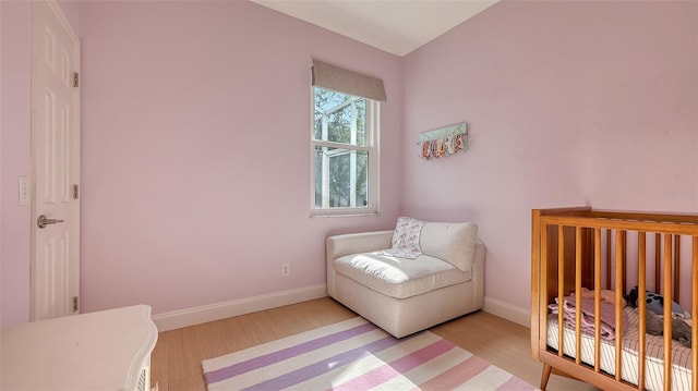 bedroom with light hardwood / wood-style flooring and a nursery area