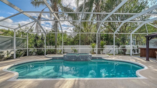 view of swimming pool featuring glass enclosure, a patio area, and an in ground hot tub