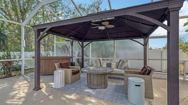 view of patio featuring ceiling fan, an outdoor hangout area, and glass enclosure