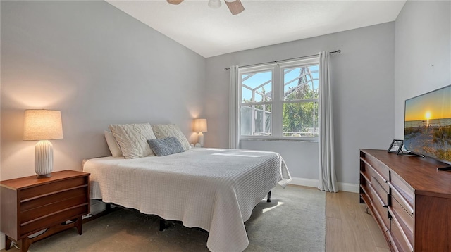 bedroom with light hardwood / wood-style floors, vaulted ceiling, and ceiling fan