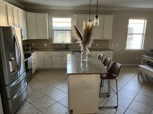 kitchen with a breakfast bar, a center island, sink, appliances with stainless steel finishes, and decorative light fixtures