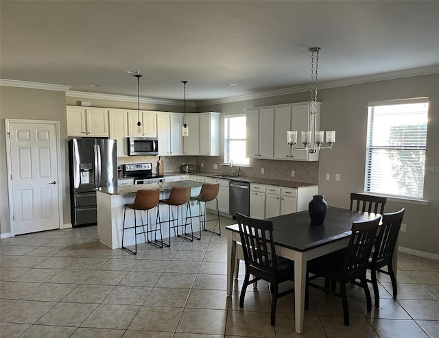 tiled dining area with ornamental molding, sink, and a chandelier