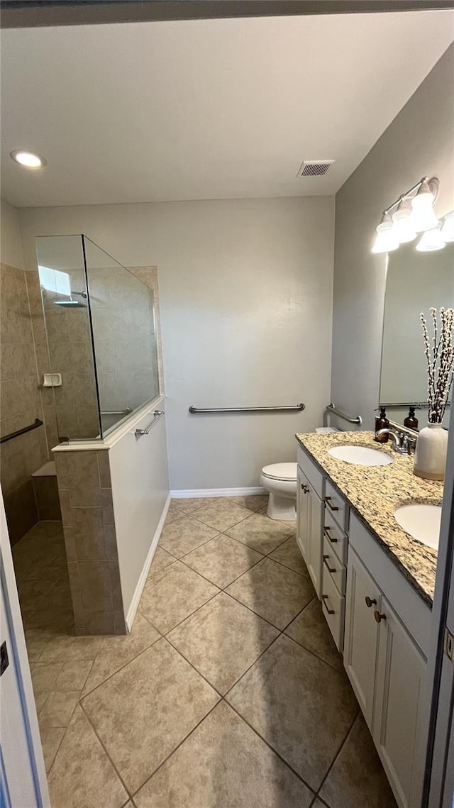 bathroom with tile patterned floors, vanity, toilet, and tiled shower