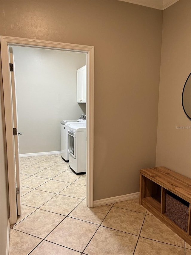 laundry room featuring cabinets, light tile patterned floors, and washing machine and clothes dryer