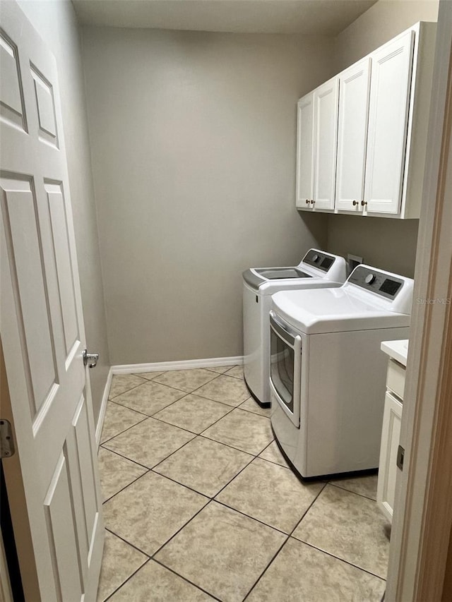 laundry area featuring washer and dryer, light tile patterned floors, and cabinets