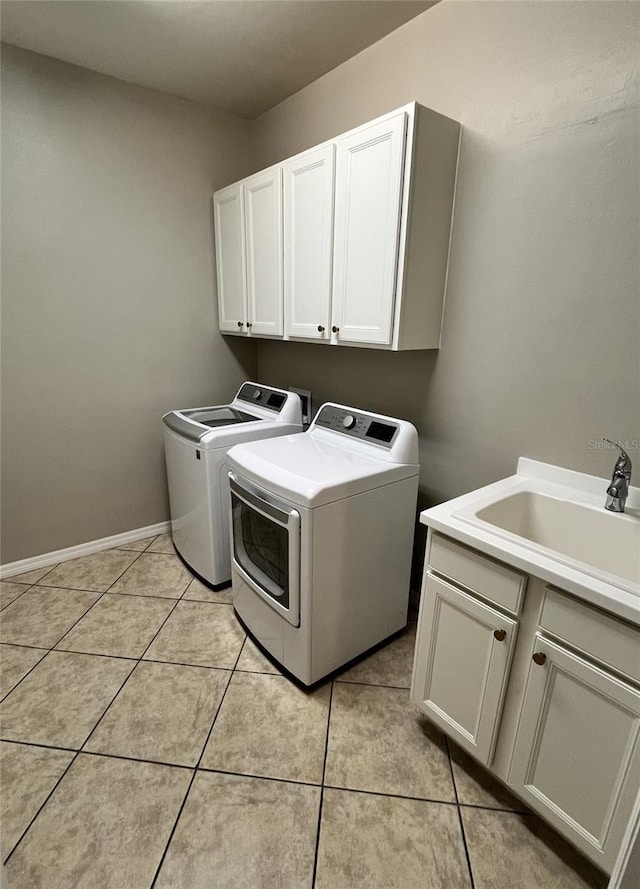 clothes washing area with washer and dryer, light tile patterned flooring, cabinets, and sink