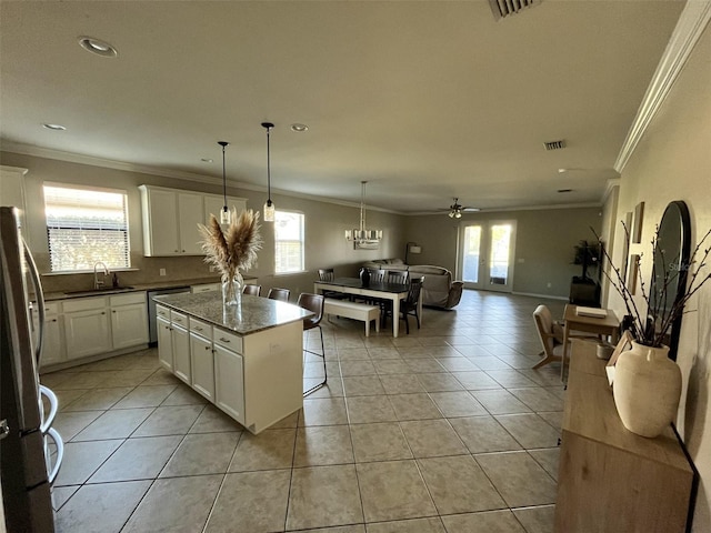 kitchen featuring appliances with stainless steel finishes, a kitchen island, sink, light tile patterned floors, and white cabinetry