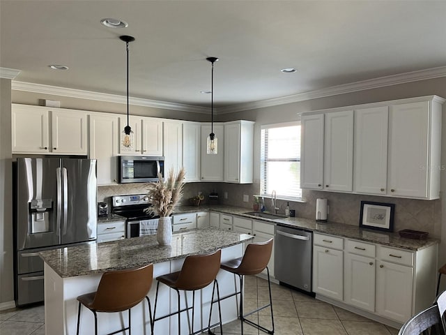 kitchen featuring a center island, white cabinets, sink, decorative light fixtures, and stainless steel appliances