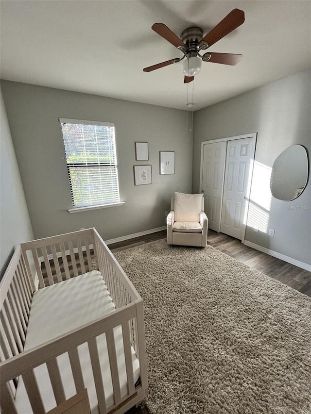 bedroom featuring hardwood / wood-style floors, ceiling fan, a closet, and a nursery area