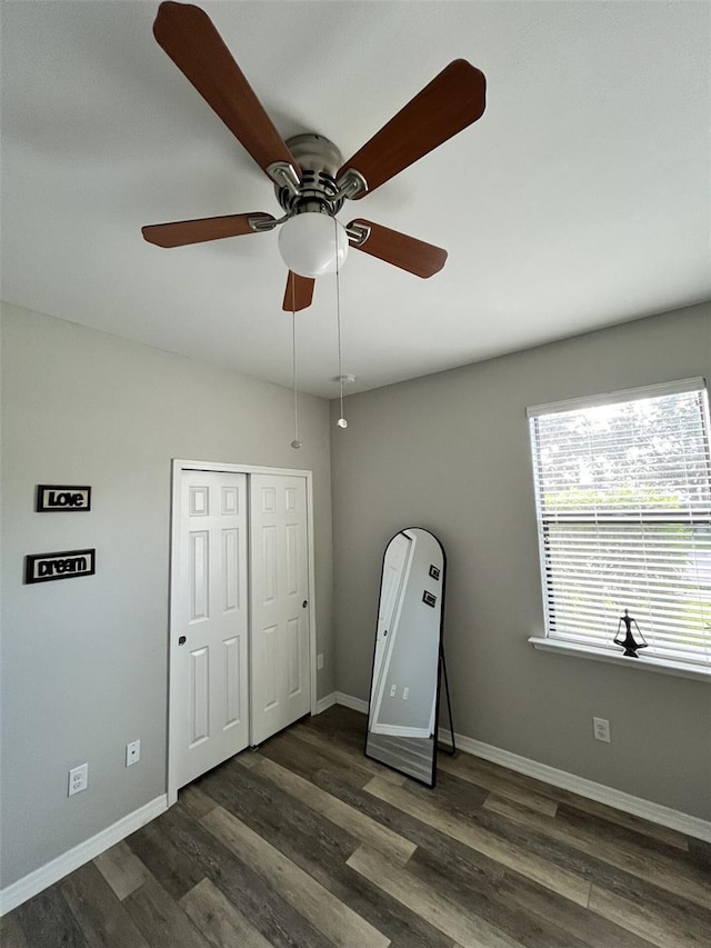 unfurnished bedroom with dark hardwood / wood-style flooring, a closet, and ceiling fan