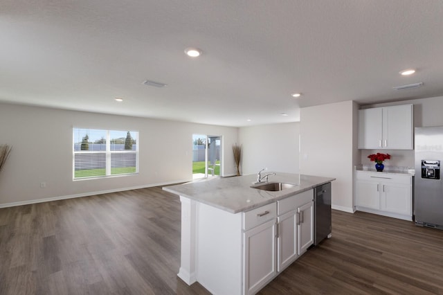 kitchen with white cabinets, a center island with sink, sink, light stone counters, and stainless steel appliances