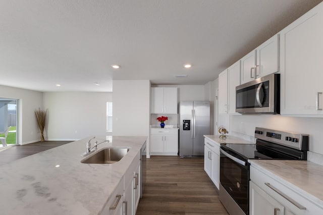 kitchen with white cabinets, sink, appliances with stainless steel finishes, plenty of natural light, and light stone counters