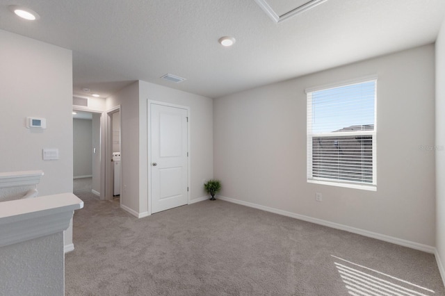 spare room with light carpet and a textured ceiling