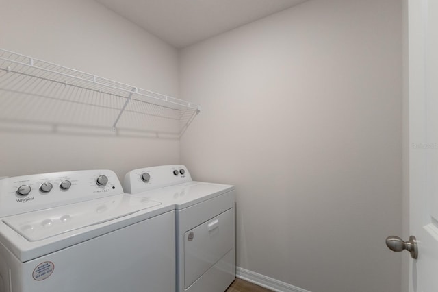 laundry room with washing machine and clothes dryer and dark wood-type flooring